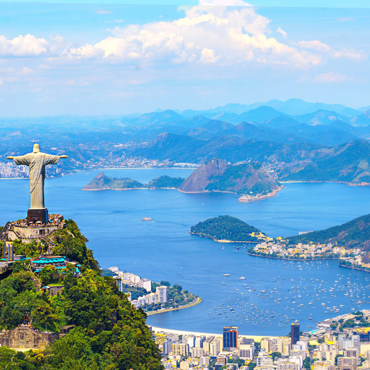 A panoramic view of Rio de Janeiro featuring the Christ the Redeemer statue on Corcovado Mountain overlooking the city and bay.