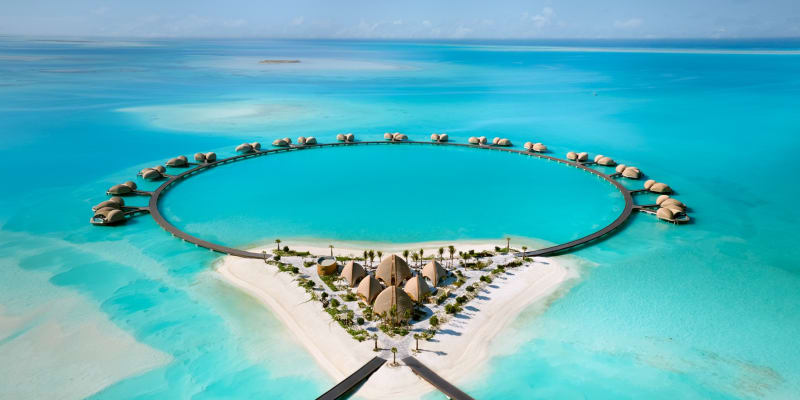 Luxushotel mit Wasserbungalows und einem großen kreisförmigen Pool am Strand am Roten Meer.