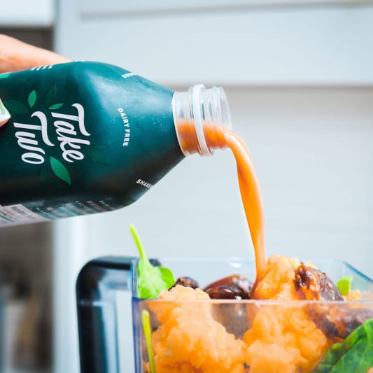 Pouring Take Two Barleymilk into a smoothie.