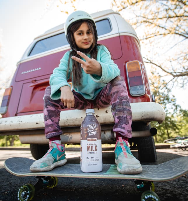 Girl on skateboard with bottle of Take Two.