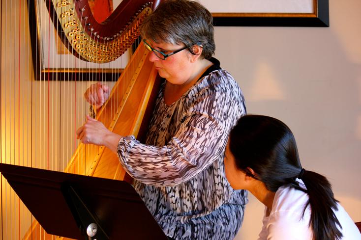 Harp Teacher Tisha demonstrates a harp technique for Lauren