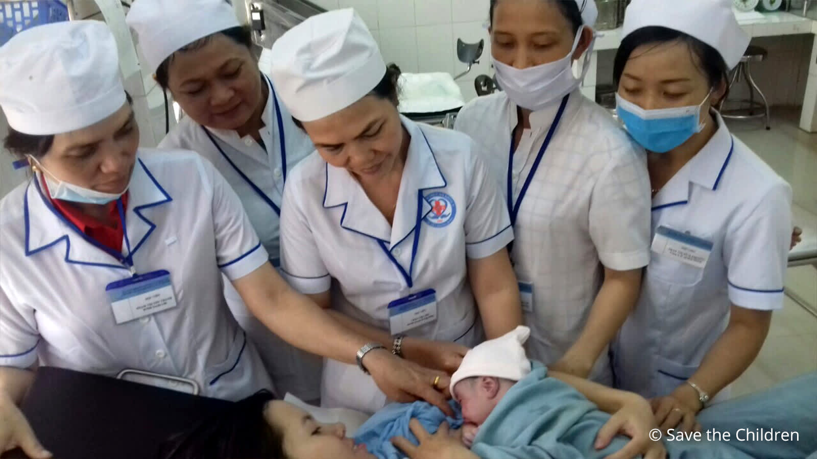 Five nurses next to newborn baby and mother 