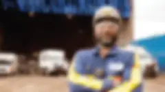 an african american male worker stands outside a warehouse with his arms crossed