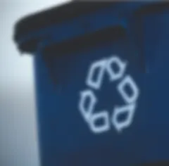 A close-up view of a blue recycling bin with a white recycling symbol of three arrows forming a triangle