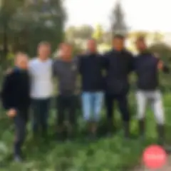 5 men stand side by side in a natural forest setting, wearing casual outdoor clothes and wellington boots