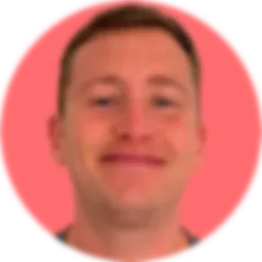 close up of face and neck of smiling Caucasian male with short brown hair and dark grey eyes, on a background that is a coral-colored circle