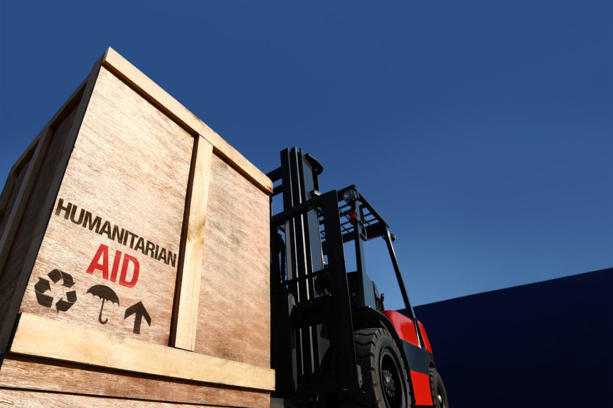 Photo of forklift carrying a wooden crate with "Humanitarian Aid" printed on the side panel