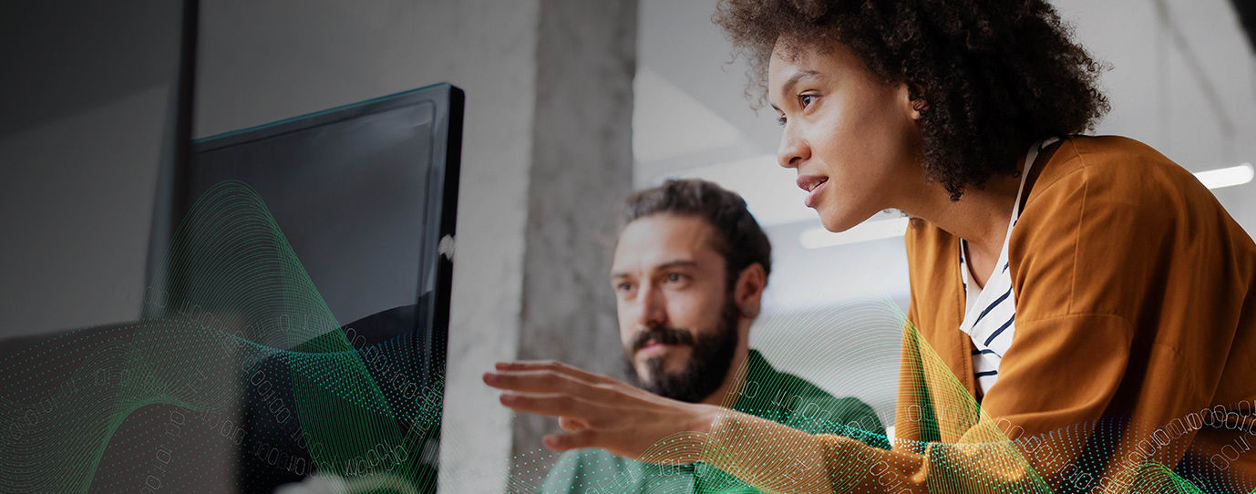 Two people are working together at a computer, with the woman pointing at the screen and the man observing. A wave-like digital graphic overlays the bottom of the image.