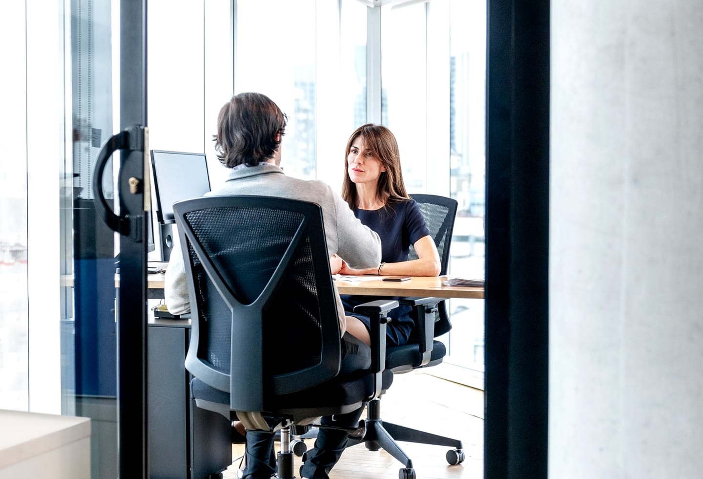 Two people talking across a desk in an office