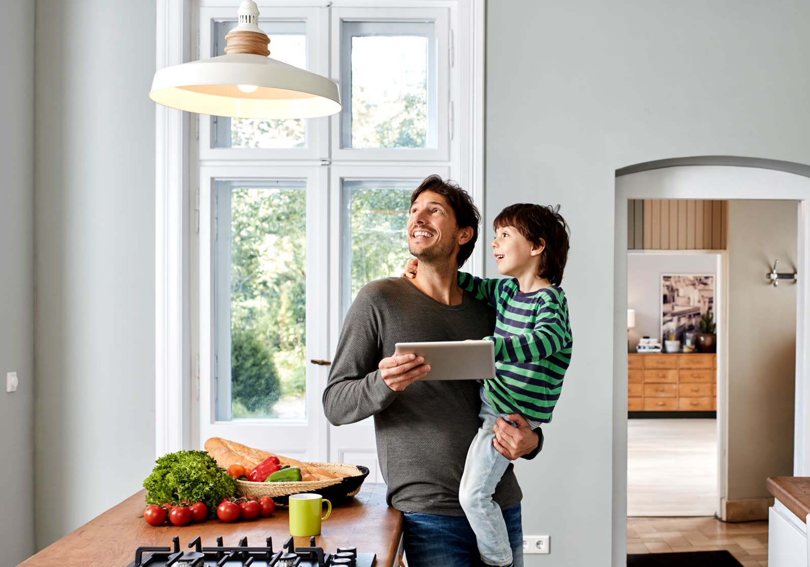 A man holding a small boy looking at a hanging light fixture