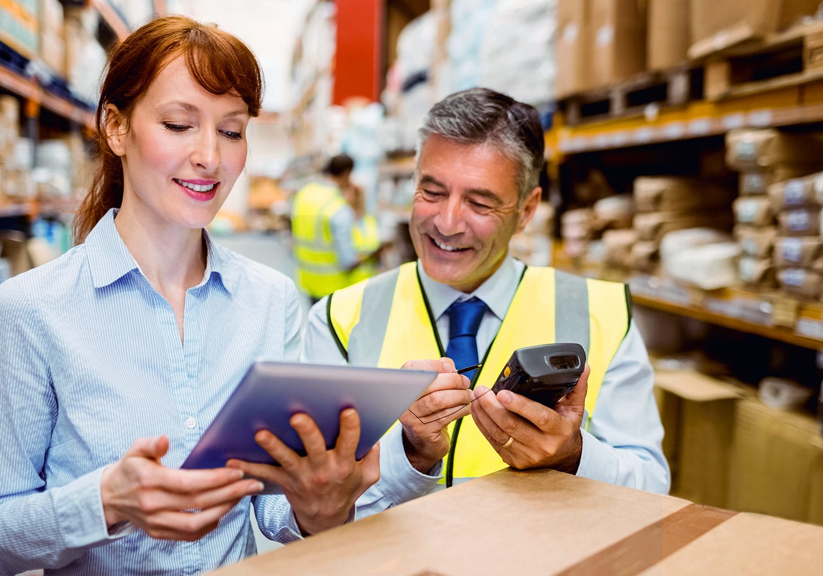 Two people in a warehouse reviewing information on a tablet