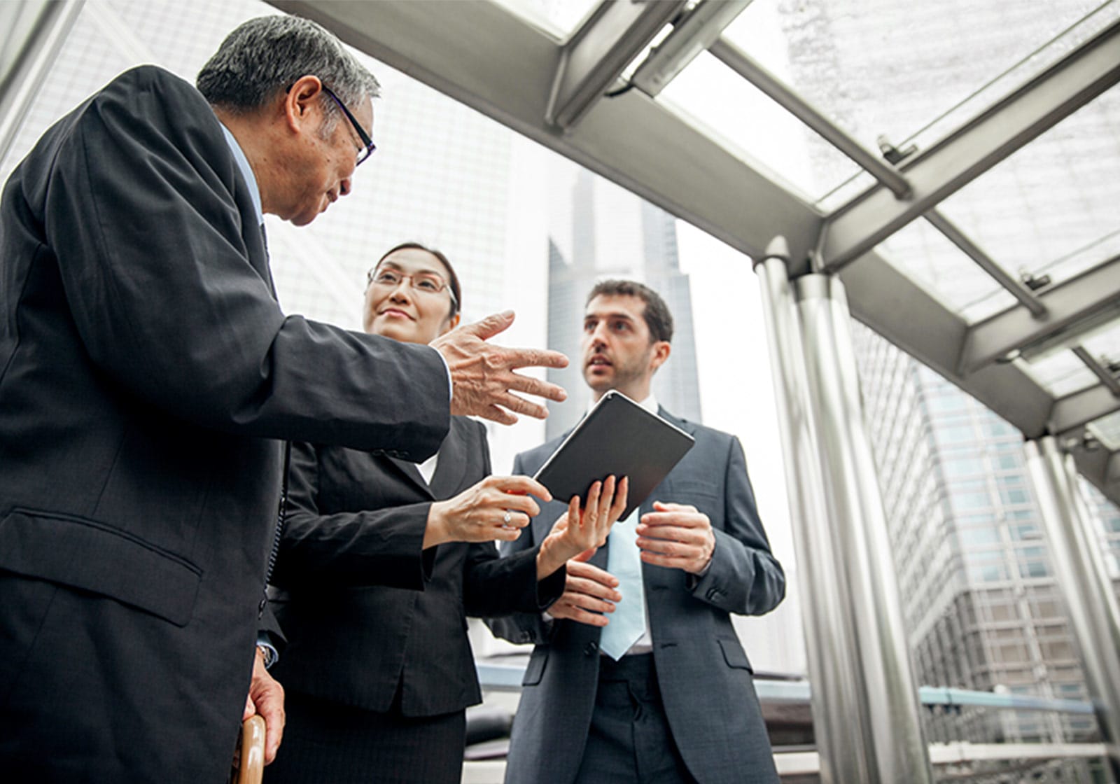 Three professionals talking in front of a wall of windows