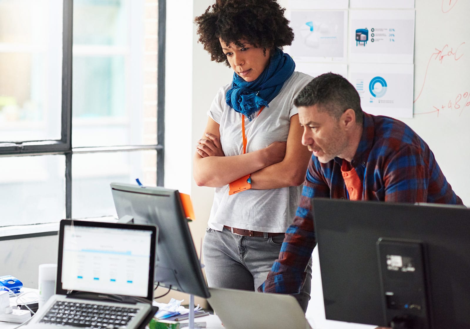 Two people in a business office looking at a computer monitor at a workstation