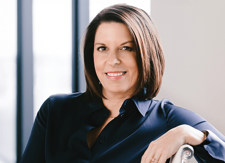 Headshot of Qlik Board of Directors member, Kristin Weston. She has short brown hair, wearing a dark shirt, and is seated and smiling in front of large windows.