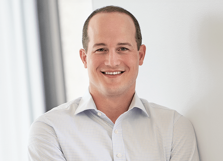 Headshot of Qlik Board of Directors member, Mike Hoffman. He has short hair, is smiling, and is dressed in a light-colored dress shirt while standing against a white background.