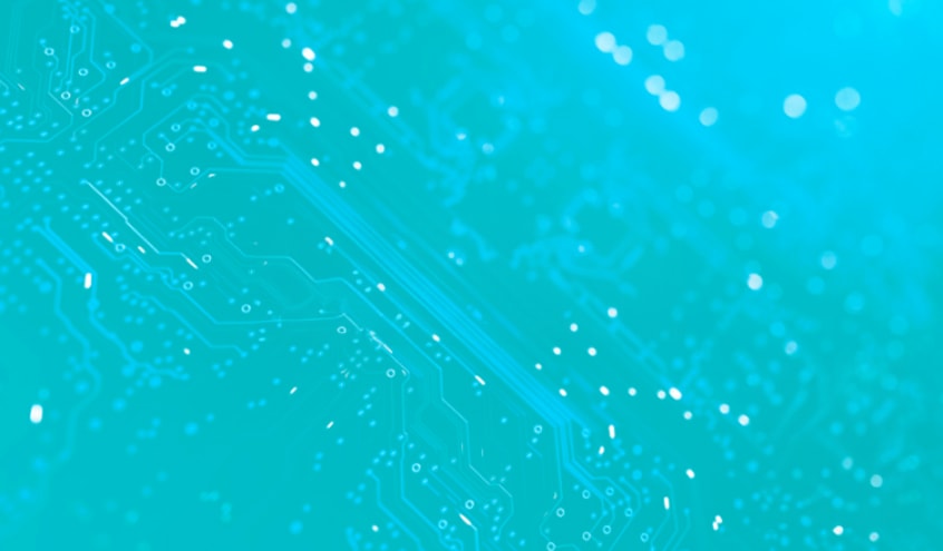 Close-up of a turquoise printed circuit board with intricate patterns and highlighted pathways against a soft, glowing background.