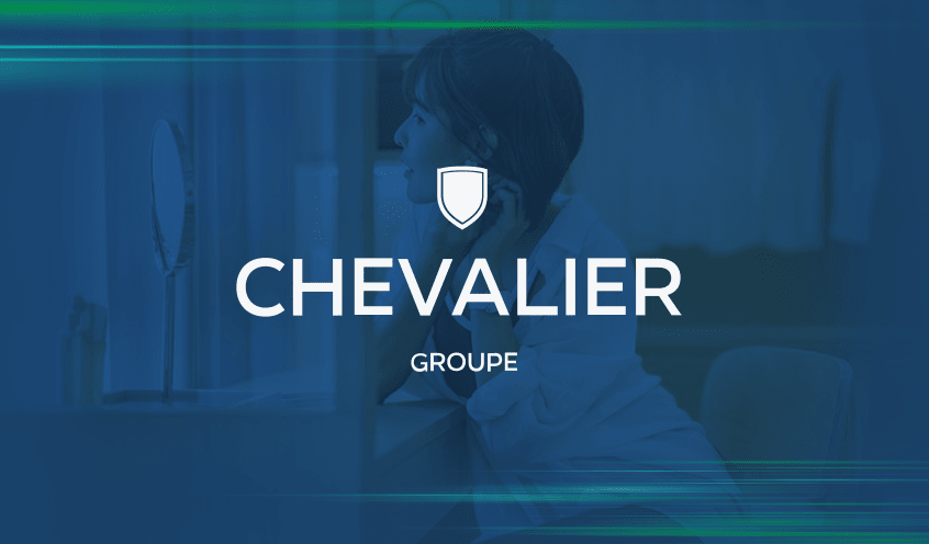 Groupe Chevalier logo with a woman is seated at her vanity and gazing into a mirror as she puts on her earrings in the background.
