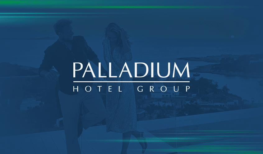 A background of a man and woman enjoys a scenic view of the ocean from the rooftop balcony of the hotel with a blue overlay features the Palladium Hotel Group logo in white in the center.