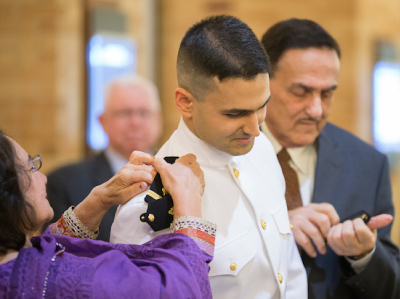 A medical student receiving his miliary commission. His parents putting his epaulettes on his uniform