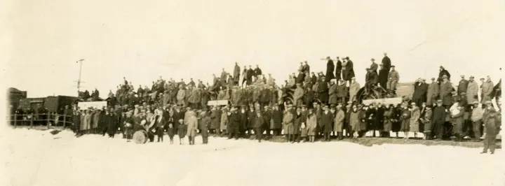 Saturday, November 29, 1913 was a historic day for residents of Shaunavon and area as the steel and track layer for the C.P.R. railroad arrived at the community. The December 4 edition of _The Shaunavon Standard_ recounts the scene as follows: "Greeted by a large number of citizens and local residents, the track layer passed through Shaunavon Saturday. It was marked by a feeling of rejoicing by both the farmers and business men. For months and years many of the local people had looked and waited for the time when the iron horse would bring them in touch with civilization." The above photograph shows the large group of people assembled to witness this important event - notice the band with instruments positioned in front of the group.  
  
Weekly updates in _The Shaunavon Standard_ newspaper chronicled the progress of track construction.