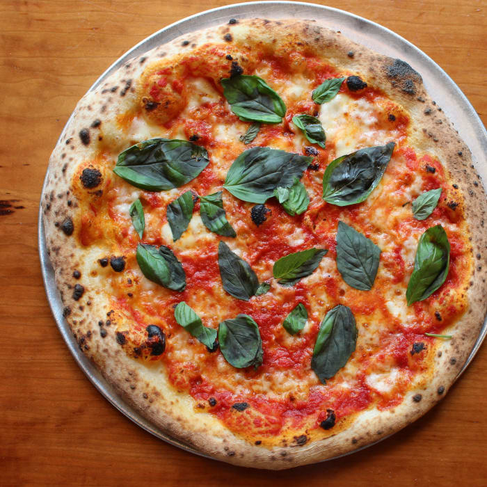 Margherita pizza — San Marzano, fresh mozzarella, basil, on a warm wood table