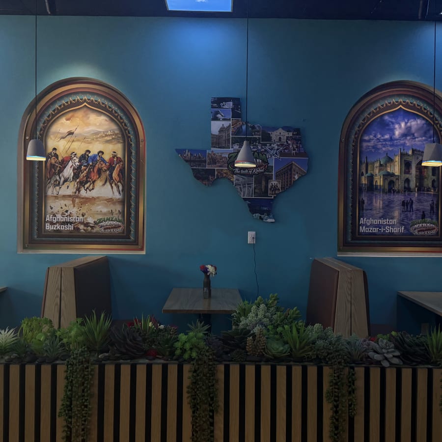 Three arched paintings of Afghan cities on the teal wall