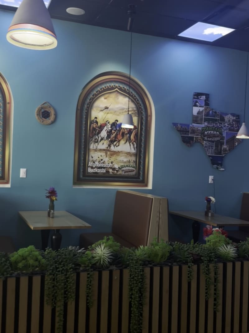 An arched painting of Afghanistan above a booth and a planter