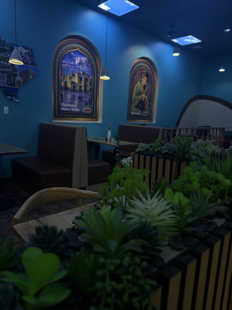 Planters of greenery between the booths and the arched murals