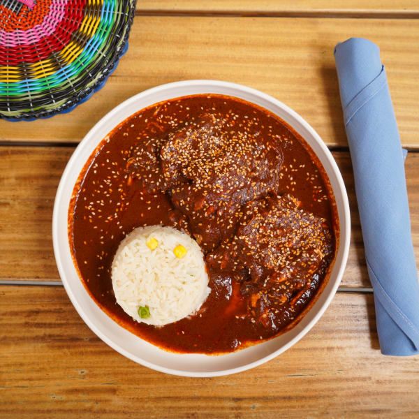 Chicken mole coloradito with sesame seeds and a scoop of rice