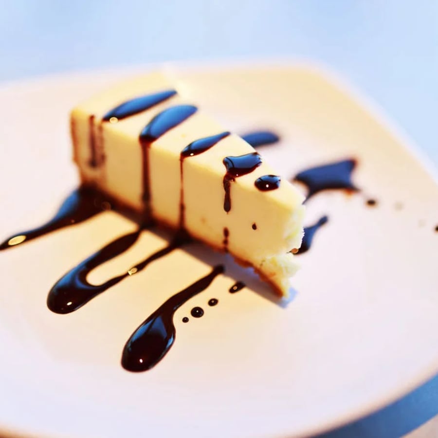 A slice of cheesecake with chocolate sauce at Lucy's