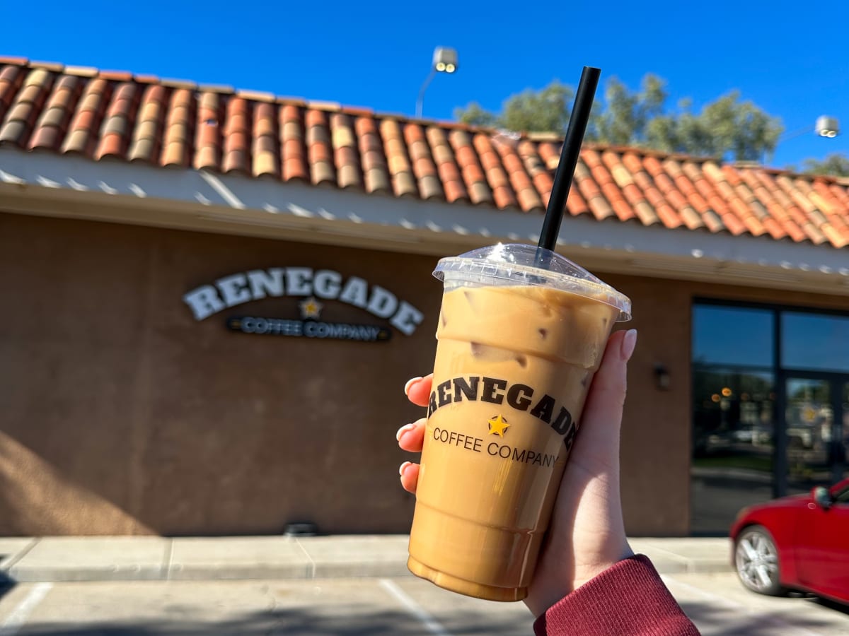 An iced Renegade coffee held up outside a Renegade shop