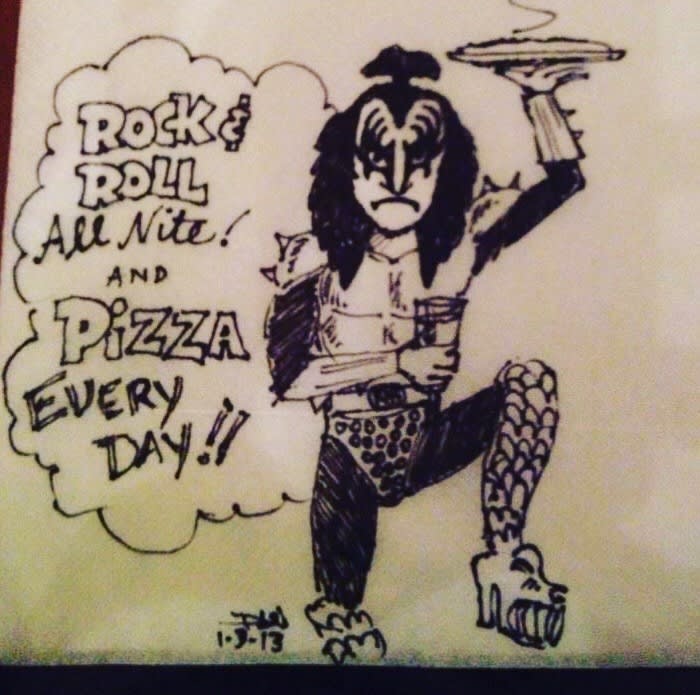 Napkin cartoon of a KISS rocker holding a pizza: Rock and Roll All Nite and Pizza Every Day