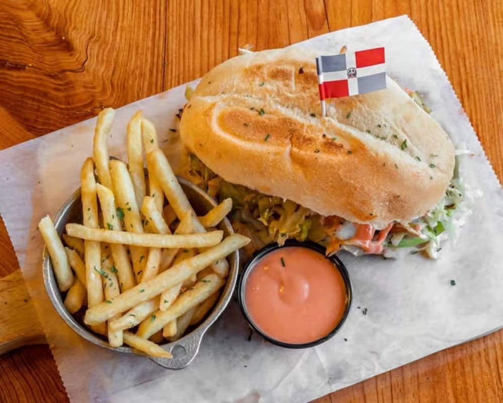 Dominican sandwich with a flag pick, fries and dipping sauce