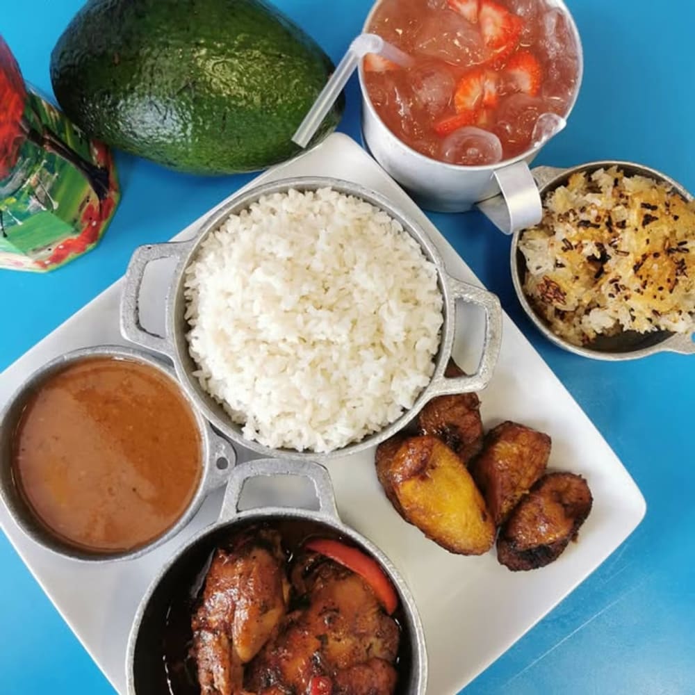 Rice, beans, stewed chicken and sweet plantains on a blue table