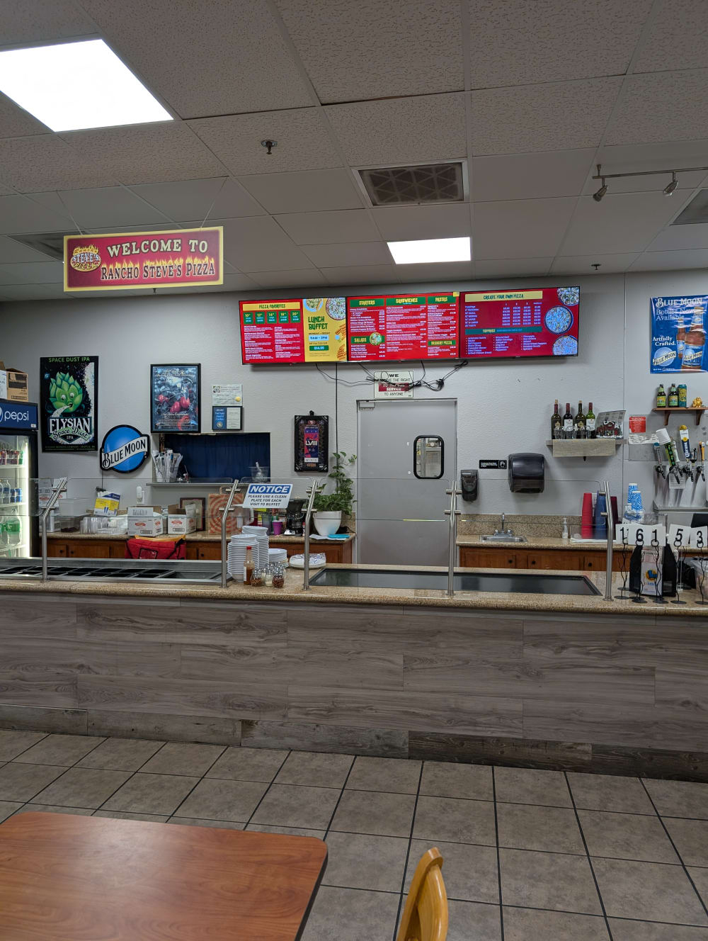 Order counter at Rancho Steve's Pizza with lit menu boards above