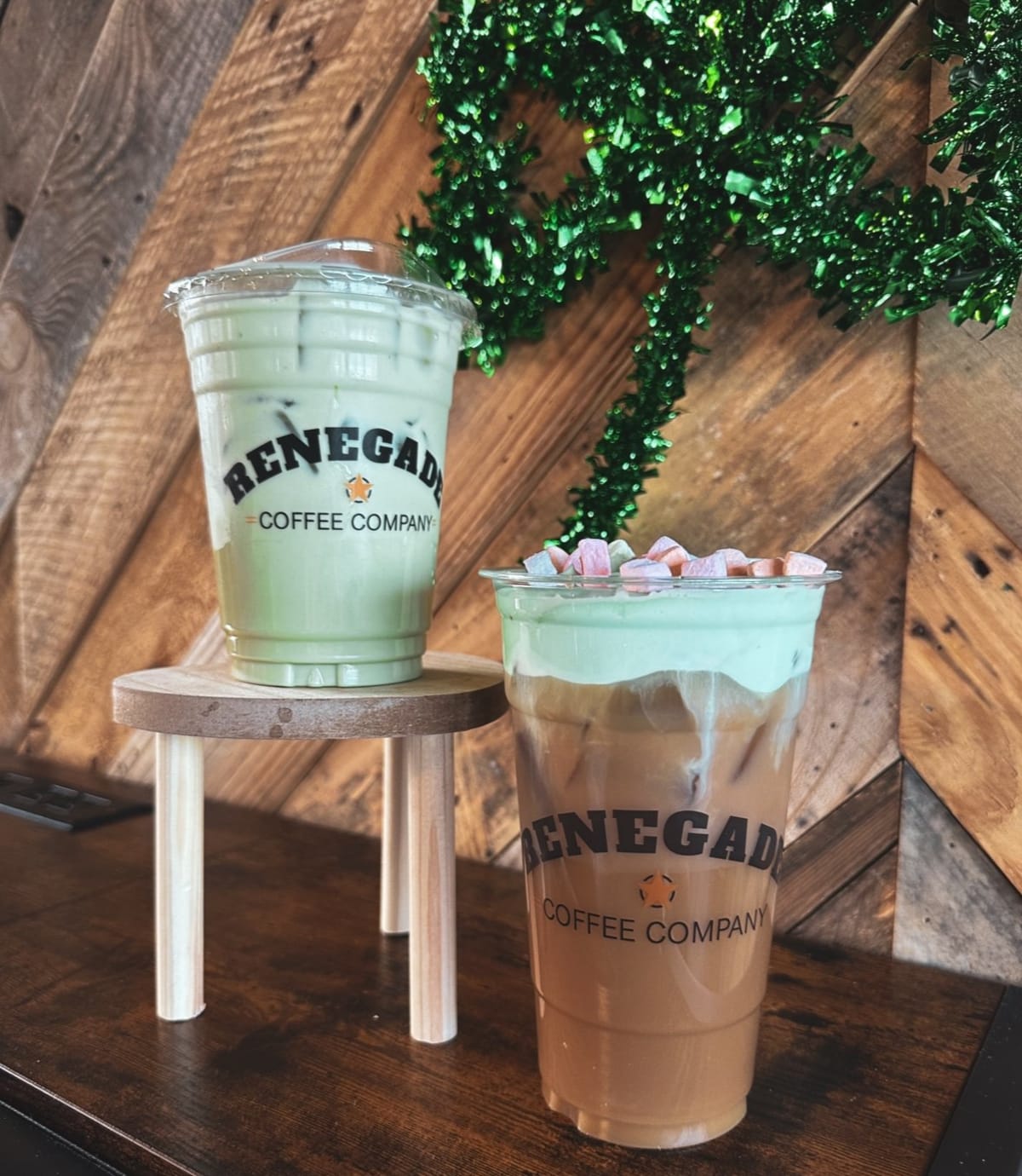 Two green Renegade Coffee drinks on a wooden stand