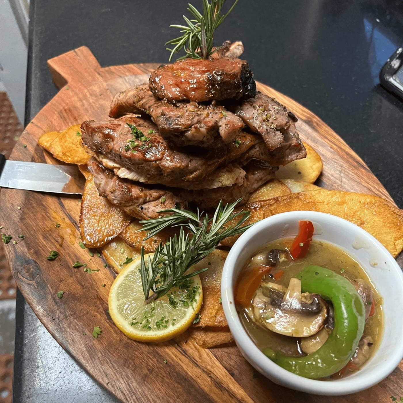 Grilled meat and potatoes with rosemary and lemon on a wooden board