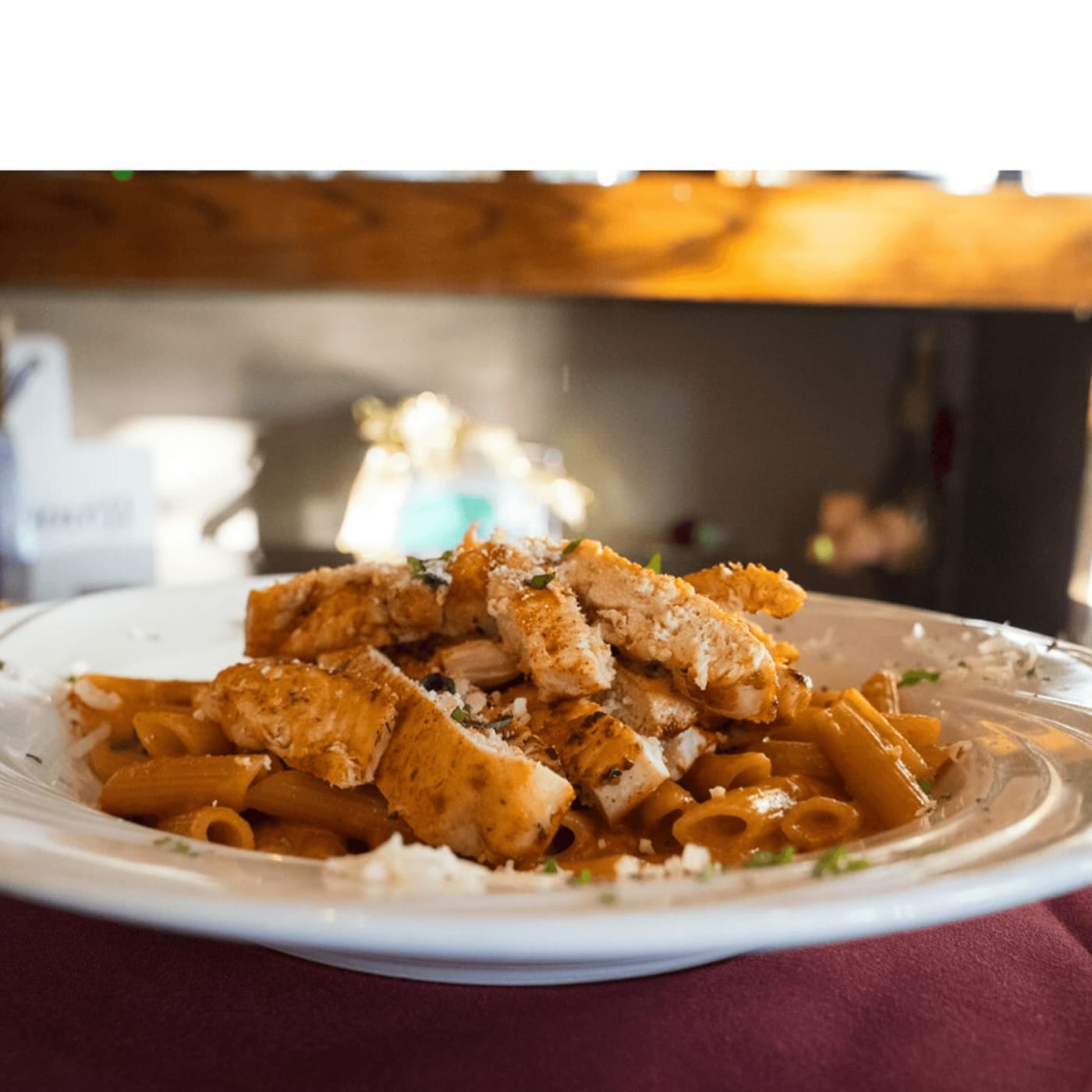 Penne with grilled chicken in red sauce under grated cheese