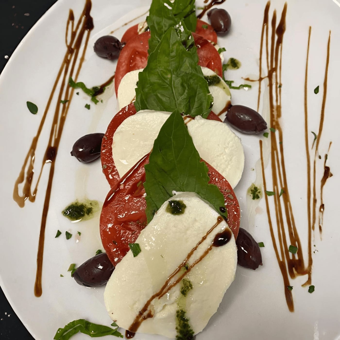 Caprese salad with fresh mozzarella, tomatoes, basil, olives and balsamic