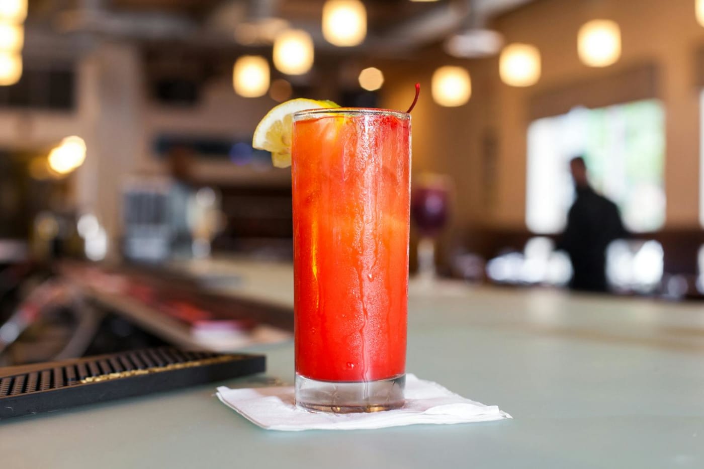 A craft cocktail on the bar at Chocolàt, the dining room behind it
