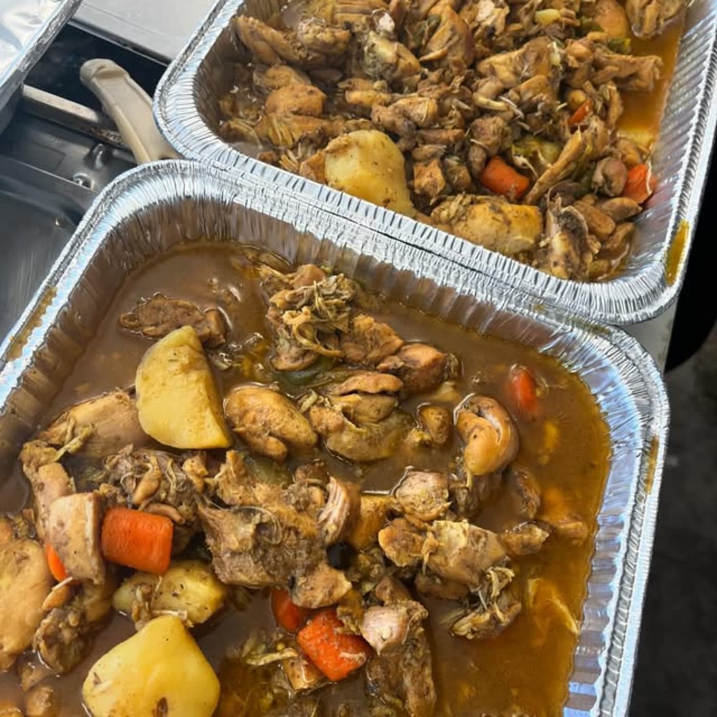 Foil catering trays of stewed chicken with potatoes and carrots
