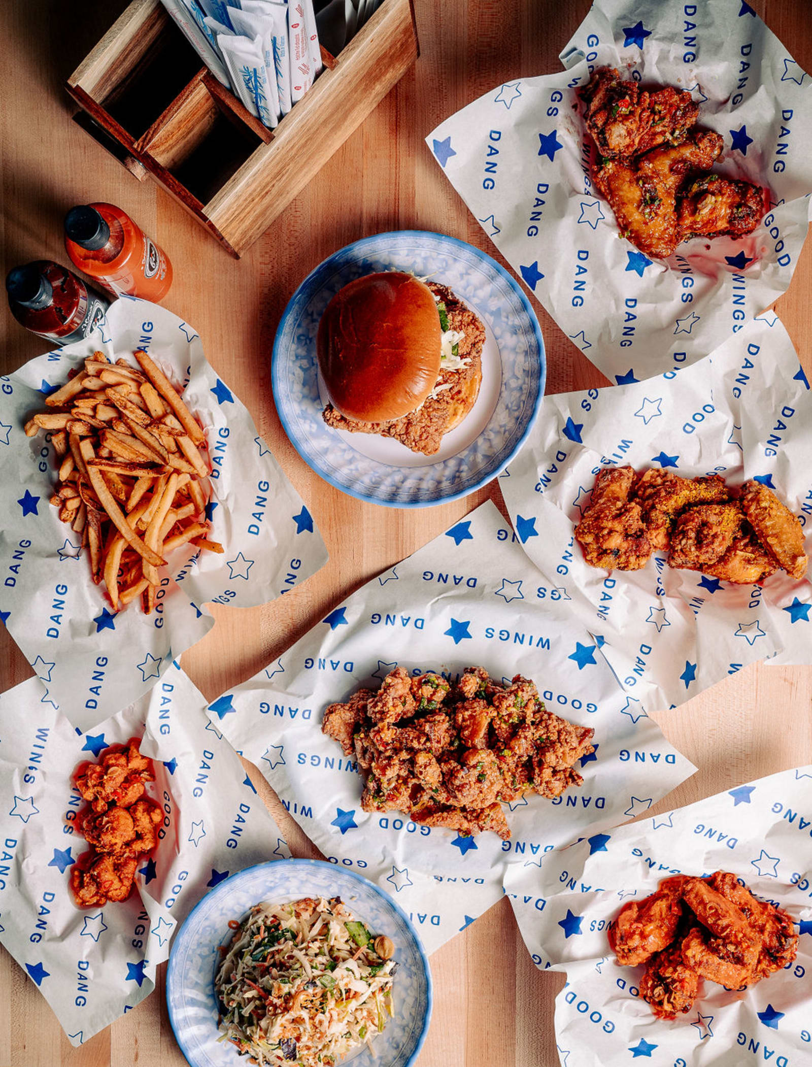 Dang Good Wings, a fried chicken sandwich, fries and slaw spread across the table at Cà Phê Đá