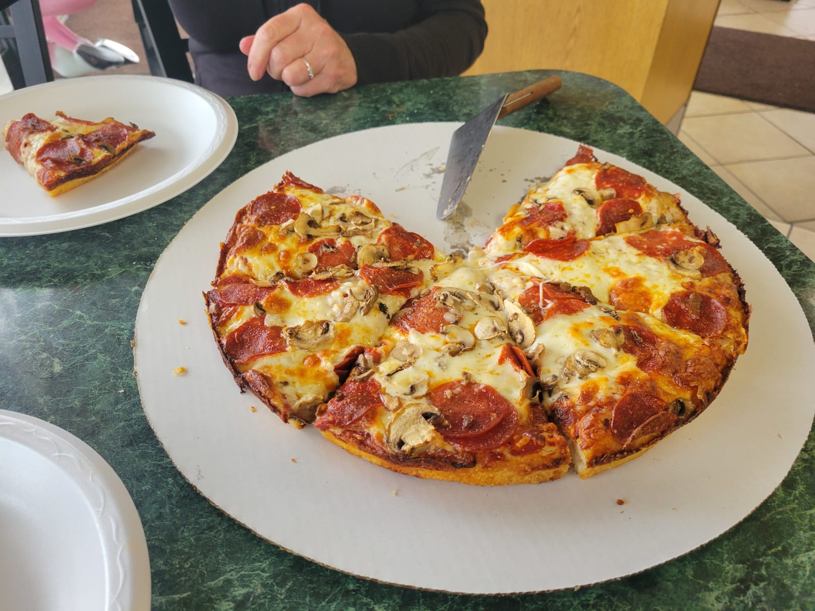 A slice being cut from a Bell's pizza on a green marble table