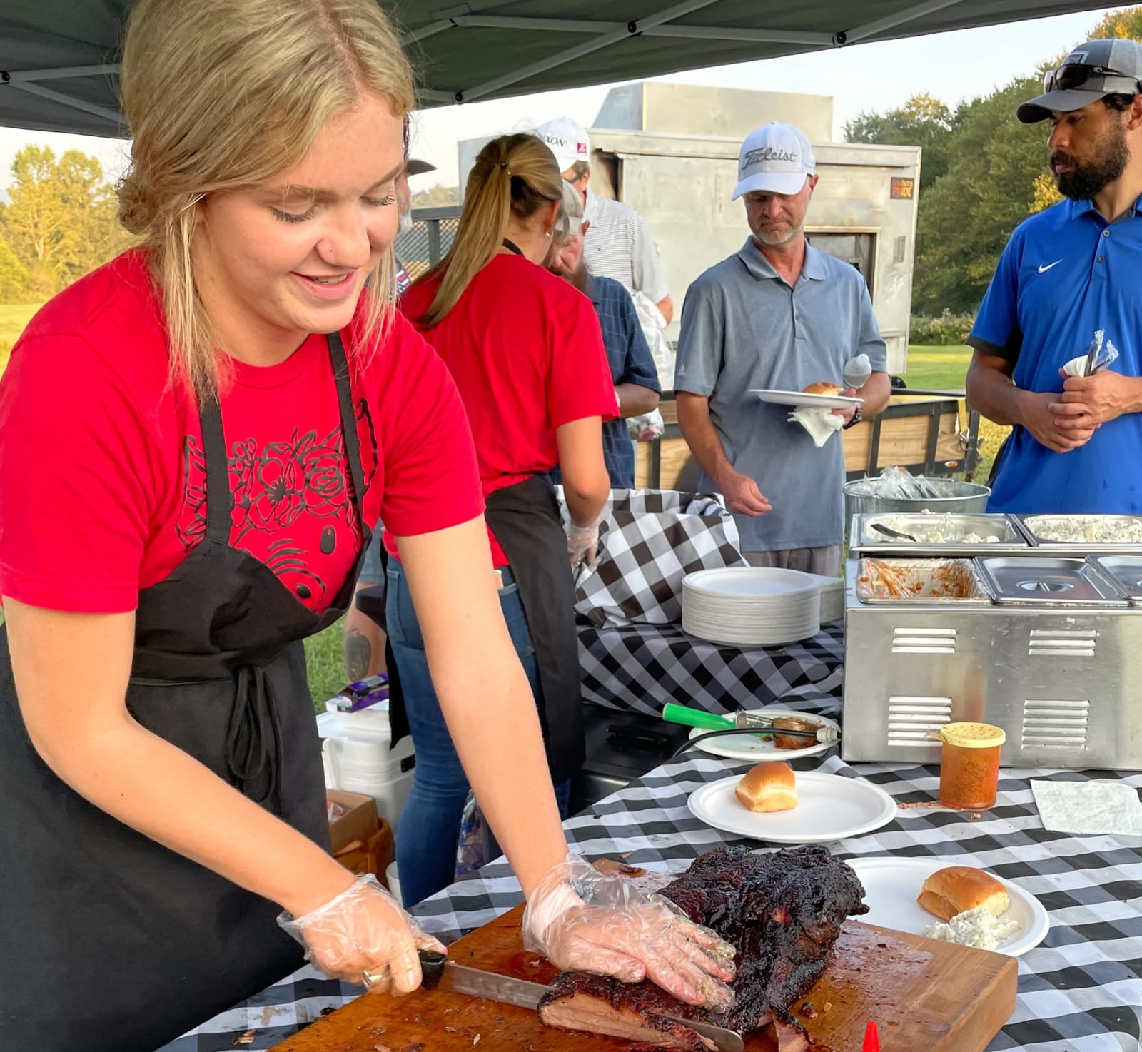 Big Nick's crew carving smoked brisket at an outdoor catering event