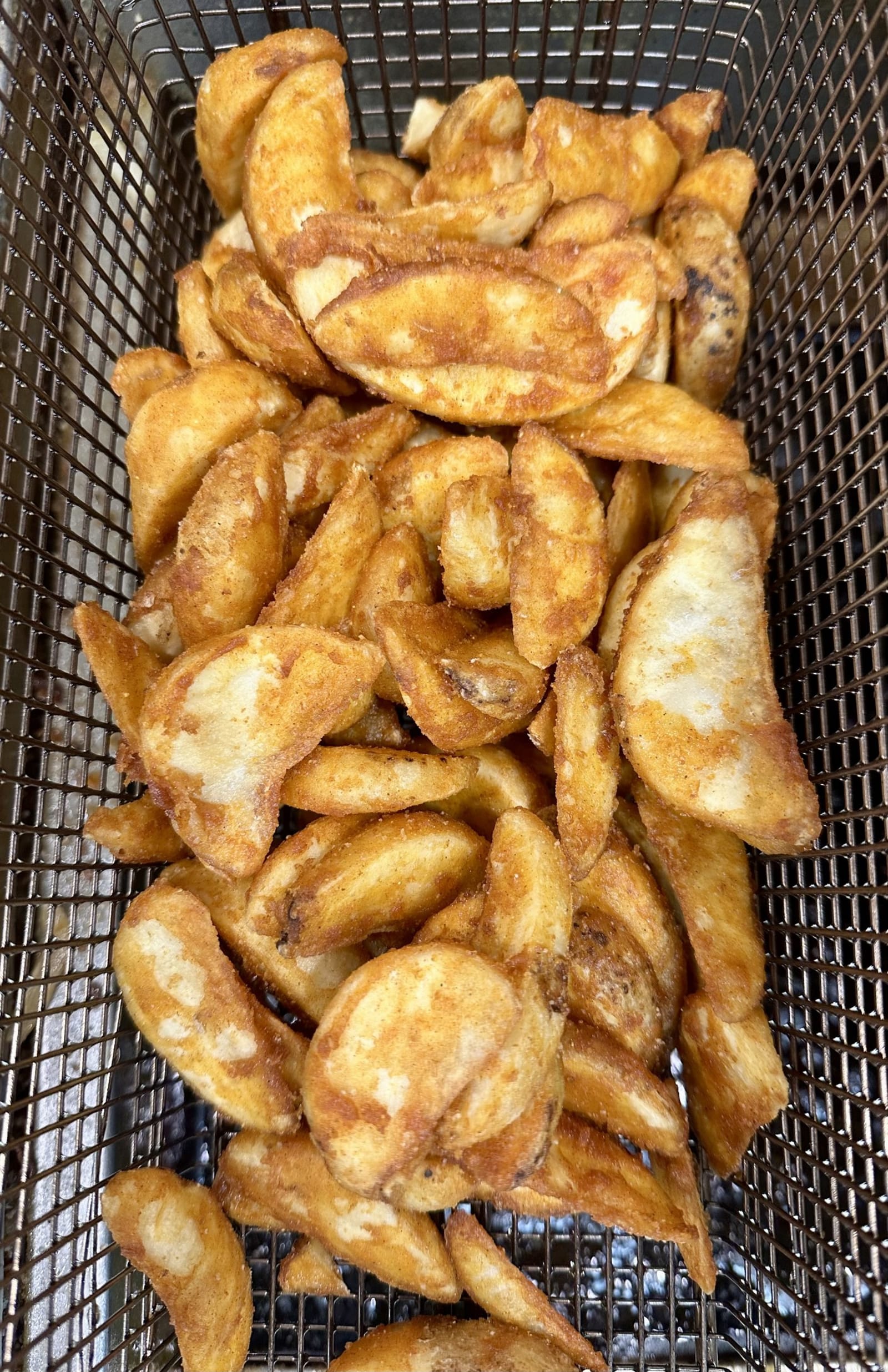 Seasoned potato wedges fresh out of the fryer basket