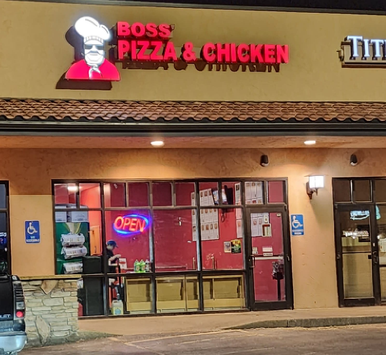 The Boss' Pizza & Chicken storefront with its lit sign