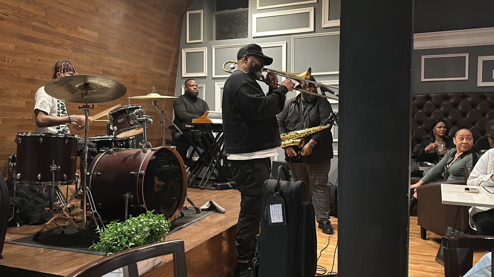 A live band playing horns and drums on the stage in the dining room