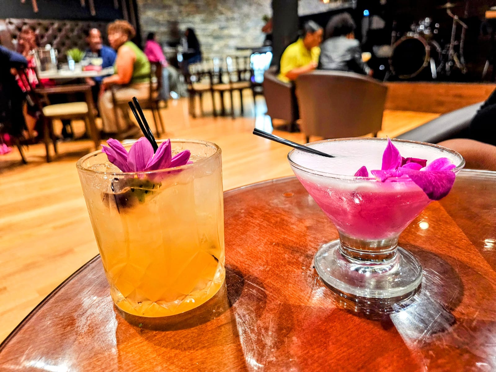 Two cocktails with orchid garnishes on a copper table