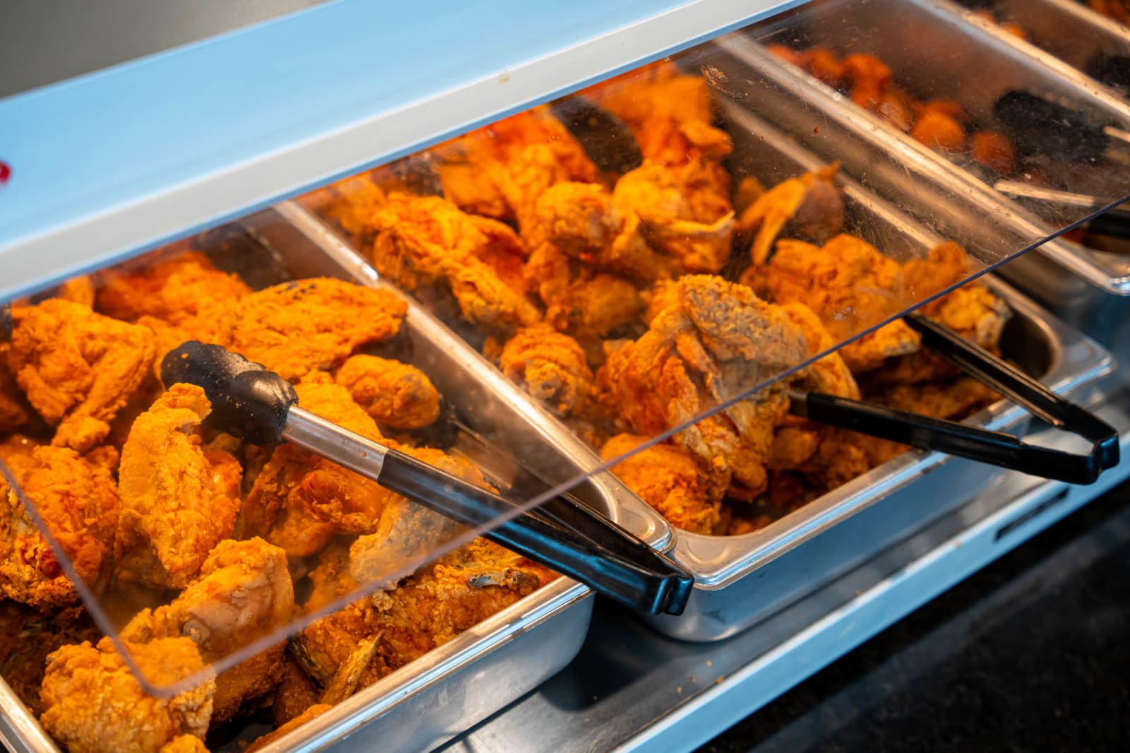 Fried chicken in a serving pan with tongs