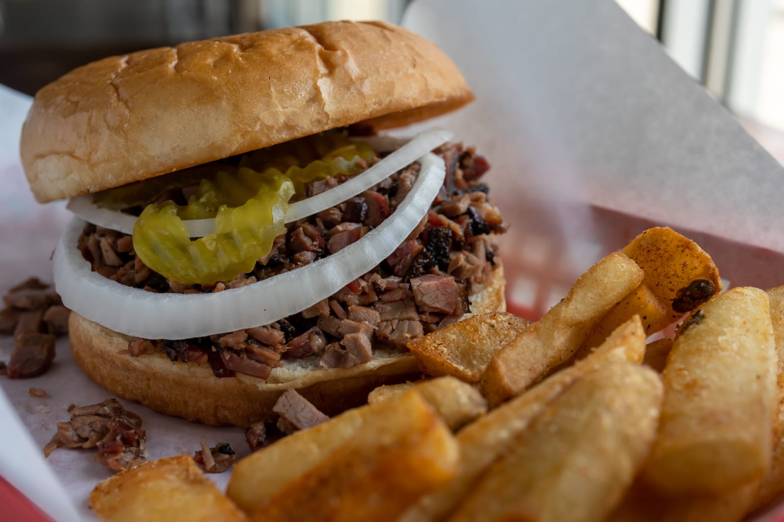 Smoked sausage sandwich with onion and jalapeno, served with potato wedges